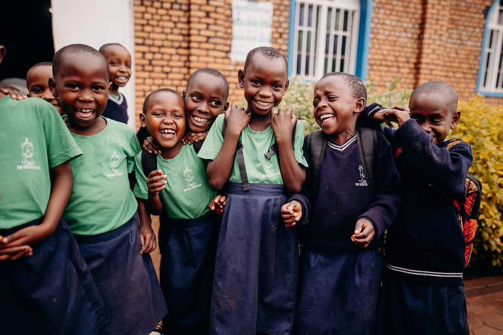 alt="Ein Tag im Compassion Kinderzentrum in Ruanda. Kinder stehen in Schuluniform zusammen und lachen"