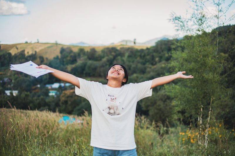 alt="Warum stehen Kinder in Armut bei Compassion im Blickpunkt? Kinder im Blickpunkt, ein Mädchen steht auf einer Wiese mit einem T-Shirt mit einer Katze drauf"