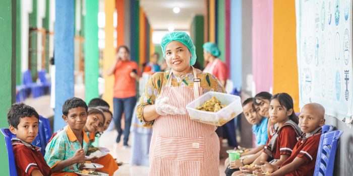 alt="Kochen aus Leidenschaft, Köchin mit Essen in der Hand, Compassion Deutschland"