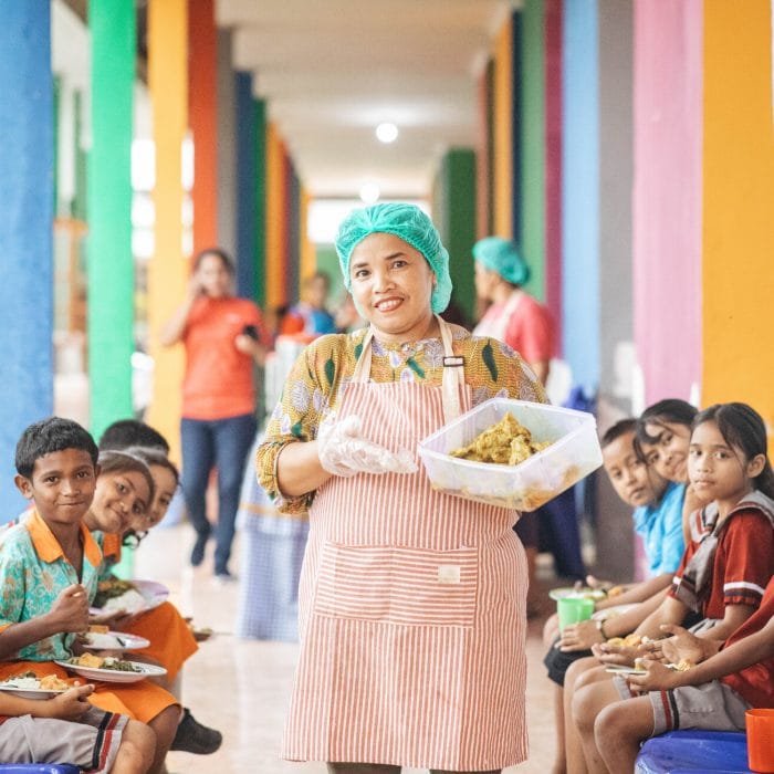 alt="Kochen aus Leidenschaft, Köchin mit Essen in der Hand, Compassion Deutschland"