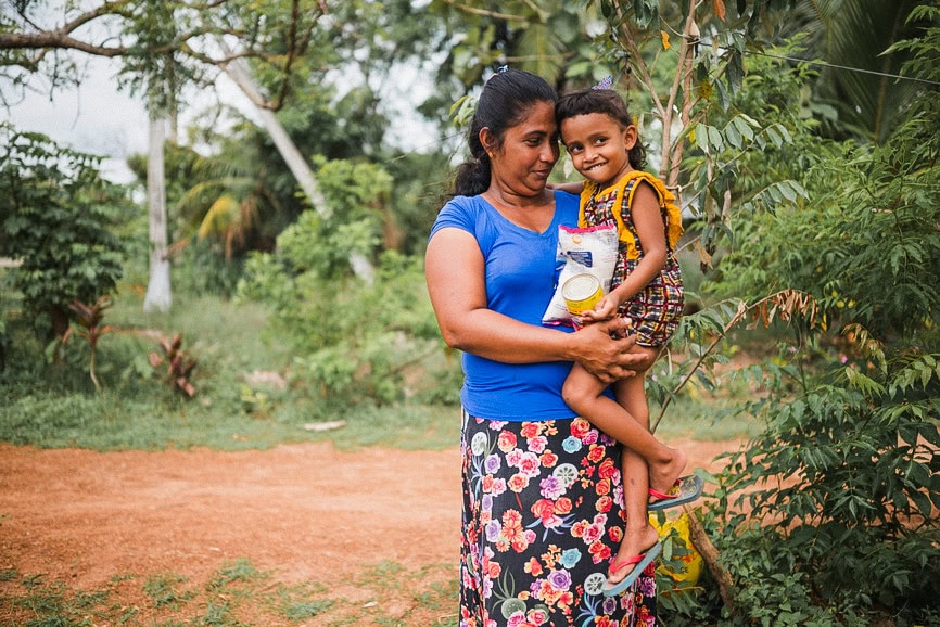 alt="Kampf gegen den Hunger, Mutter mit Kind und Lebensmitteltüten auf einem Weg in Bangladesch, Compassion Deutschland"