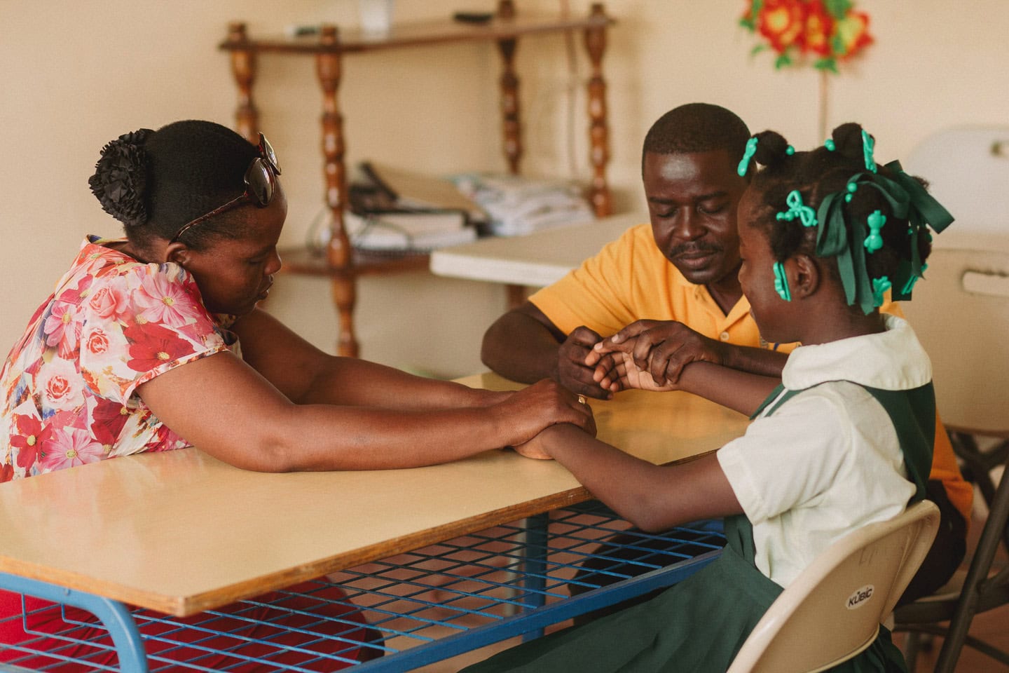 alt="Zum Neuanfang gezwungen, Zum Neuanfang gezwungen, Carolie und Laurie in Haiti, Eltern und Tochter in einem Compassion Zentrum am beten, Compassion Deutschland"