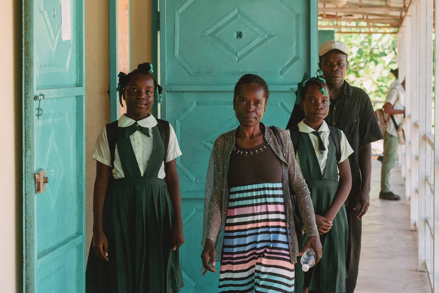 alt="Zum Neuanfang gezwungen, Carolie und Laurie in Haiti, Mädchen mit ihren Eltern stehen nebeneinander im Compassion Kinderzentrum, Compassion Deutschland"